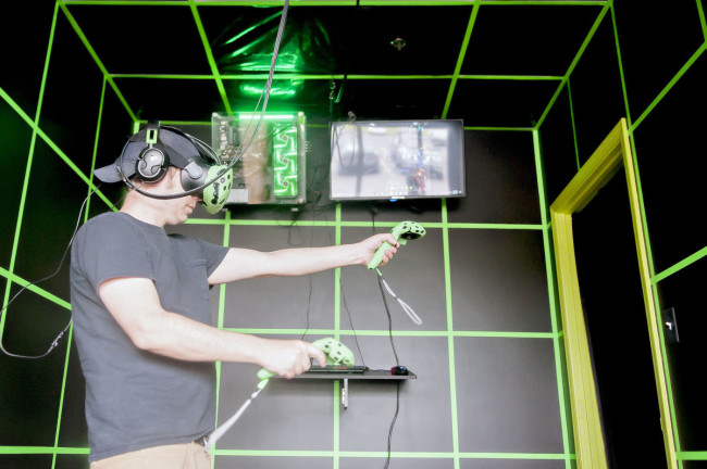 VRアーケードの個室でゲームをする男性