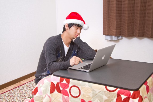 サンタ帽を被ってノートパソコンを触る男性